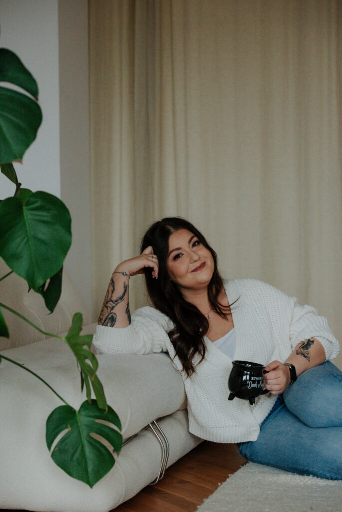 Kobieta z kubkiem, oparta o kanapę w Studio LaCasa