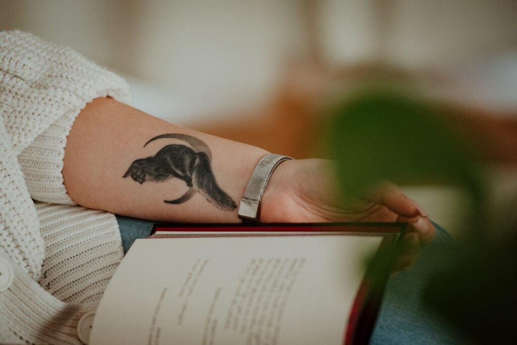 Ręka z tatuażem kota oraz fragmentem książki