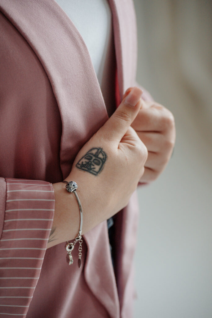 Dłoń z tatuażem hełmu Darth Vaddera oraz bransoletką z charmsami